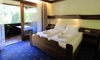 A cozy bedroom with two beds and fresh towels. The large terrace offers a view of nature.
