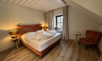 A cozy bedroom with a large bed and soft pillows. A window front provides natural light and a pleasant atmosphere.