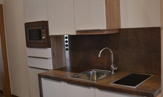 A modern kitchen with bright cabinets and a wooden countertop. It features a sink, a stove, and a microwave.