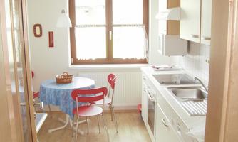 A bright kitchen with modern furniture and a round table. The windows let in plenty of daylight and create a friendly atmosphere.
