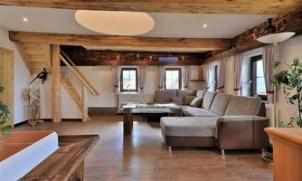 A modern living room with wooden details and large windows. A cozy couch and a table invite you to relax.