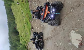 Two quads on an unpaved road amidst green meadows and trees. The riders are wearing helmets and enjoying the ride in nature.