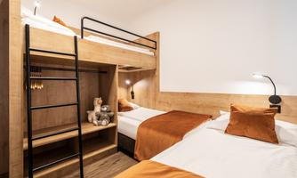 A cozy room with a loft bed and a single bed. The warm colors create an inviting atmosphere.