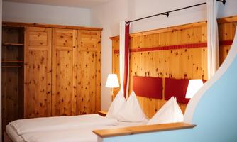 A cozy bedroom with wood paneling and two beds. The soft lighting creates a relaxed atmosphere.