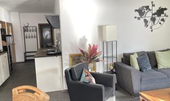 A modern apartment with a cozy living area and an open kitchen. The furniture is simple and stylish, and there is a decorative globe on the wall.