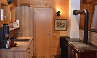 A modern kitchen with wooden shelves and a cozy atmosphere. The room features a sink, a stove, and a decorative picture on the wall.