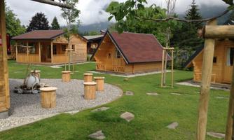 A quiet area with wooden accommodations in a green environment. The garden has seating and a small gravel area.