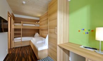 A modern room with wooden cabinets and two beds. On the wall, there is a green area decorated with colorful magnets.