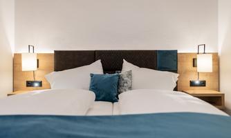 A modern bedroom with a cozy bed and decorative pillows. Soft lighting creates a relaxed atmosphere.