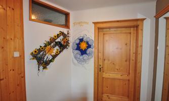 A bright hallway with wooden paneling and a decorative wall with sunflowers. On the wall, there is a painting of a sun and clouds.