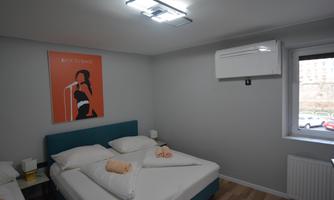 A modern room with a double bed and a bright, friendly atmosphere. A stylish piece of artwork hangs on the wall, and the room offers plenty of daylight.