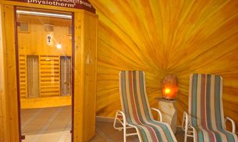 A cozy sauna with wood decor and relaxing loungers. The wall is designed in warm yellow tones that create a relaxing atmosphere.