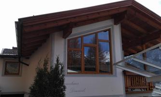 A modern house with a large window and a protective canopy. The structure has a wooden frame and a cozy atmosphere.