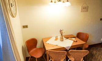 A cozy dining area with a wooden table and beige chairs. A vase of flowers and kitchen utensils give the room an inviting atmosphere.