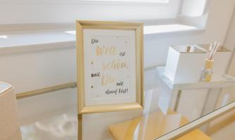 A beautiful picture frame with an inspiring quote is on a glass table. In the background, there is a window letting in daylight.