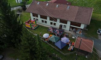 Eine verdeckte Veranstaltung mit Zelten und einem Sprungschloss. Im Hintergrund ist ein großes Gebäude und zahlreiche Gäste im Freien zu sehen.