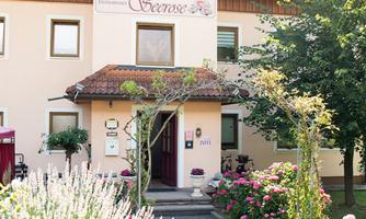 A charming building with wood cladding and an inviting entrance. The ambiance is framed by colorful flowers and well-tended plants.