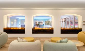 A modern room with comfortable seating and large windows. The walls display pictures of an indoor pool with stylish fire features.