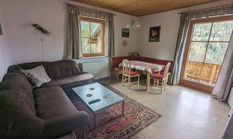 A cozy living space with a large sofa and a dining table. The light streams through the windows, creating an inviting atmosphere.