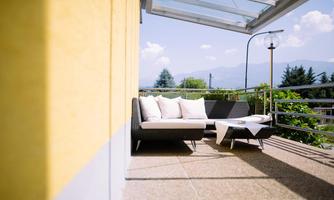 A modern terrace with a cozy seating area and coffee table. In the background, trees and mountains are visible.