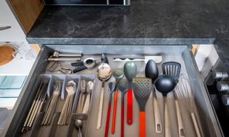 A kitchen drawer with various cooking utensils and cutlery. The utensils are neatly arranged and include spoons, forks, and ladles.