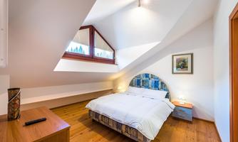 A cozy bedroom with a double bed and wooden floor.  
Large windows provide plenty of daylight and an inviting atmosphere.