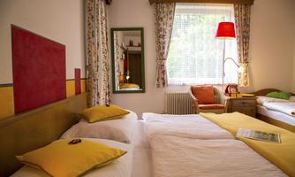 A cozy room with two beds and yellow cushions. There is a runner and a mirror, and plenty of daylight comes through the window.