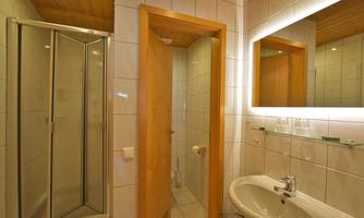 A modern bathroom with a shower, sink, and mirror. The walls are brightly tiled, and the room has a friendly atmosphere.