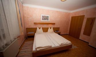 A simple room with two single beds and a soft color on the walls. The room is bright and has a carpet as well as a window with curtains.