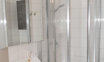 A modern bathroom with a shower cubicle and a sink. It has bright tiles and a clean, tidy atmosphere.