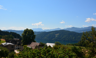 A picturesque landscape with a calm lake and gentle hills in the background. The surroundings are green and sunny, perfect for a relaxing view.