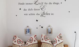 A cozy bedroom with decorative pillows and an inspiring wall text. The walls are adorned with small pictures and butterflies.