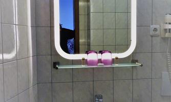 A modern bathroom with a illuminated mirror and a sink. In the background, towels and an open door can be seen.