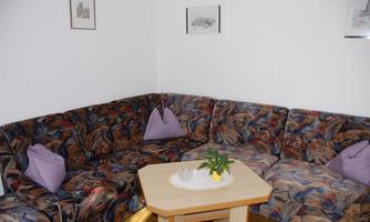 A cozy living area with a colorful corner sofa and a small table. On the table, there is a plant and some decorations.