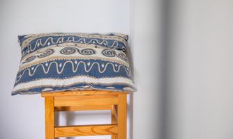 Wooden stool with patterned cushion in the hallway. A practical place to put on shoes or briefly set them down before heading out to the lake.