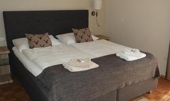 A cozy bedroom with a large double bed and modern decorations. Fresh towels are on the bed, and the atmosphere is welcoming.
