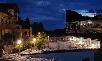 A stylish outdoor area at night, illuminated with soft light. In the background, the pool and a tranquil landscape are visible.