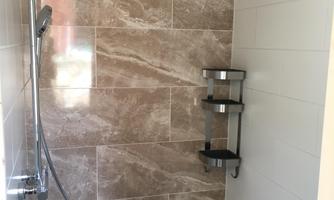 A modern shower with an elegant showerhead and smooth tiles. The gray and brown tones create a stylish ambiance.