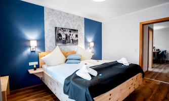 A modern bedroom with a large bed and a stylish wall color. The decor is cozy and inviting.