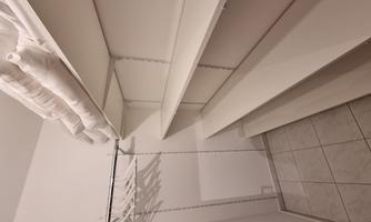 A spacious, bright closet with white shelves. 
Folded towels are stored on top.