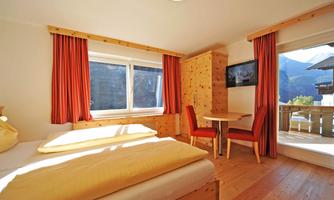 A cozy room with two single beds and wooden details. Large windows offer a view of the mountains and plenty of daylight.