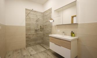 A modern bathroom with a walk-in shower and a simple sink. Bright colors and a clear design create a pleasant atmosphere.