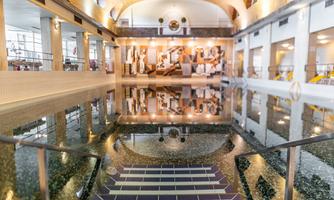 An elegant indoor pool with smooth water and modern architectural elements. In the background, artistic wall designs can be seen.