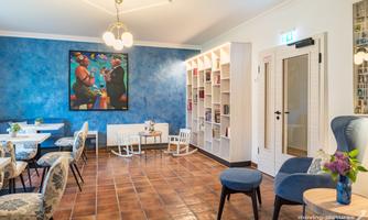 A stylish café with blue walls and modern furniture. On a table, there is a vase with fresh flowers.