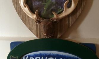 A decorative heart-shaped wall plate with the inscription "Kornblume" and a deer antler. Below it is another sign featuring the same word in a different color scheme.