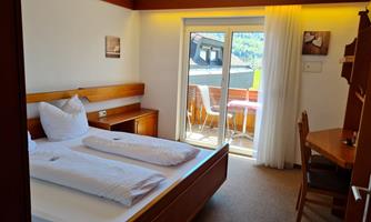 A bright hotel room with a double bed and a balcony. The room features a table and chairs as well as a friendly atmosphere.
