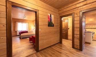 A cozy hallway with wooden walls and a warm ambiance. On the left side, doors to the bedrooms and a living area are visible.