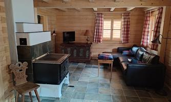 A cozy room with wood paneling and a stove. In the background, there is a black sofa and a TV.