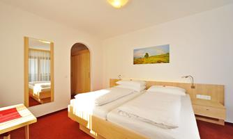 A modern bedroom with two beds and a wood design. The walls are light, and a picture hangs above the bed.