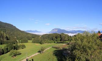 A picturesque landscape with gentle hills and lush greenery. In the background, mountains and a clear sky can be seen.